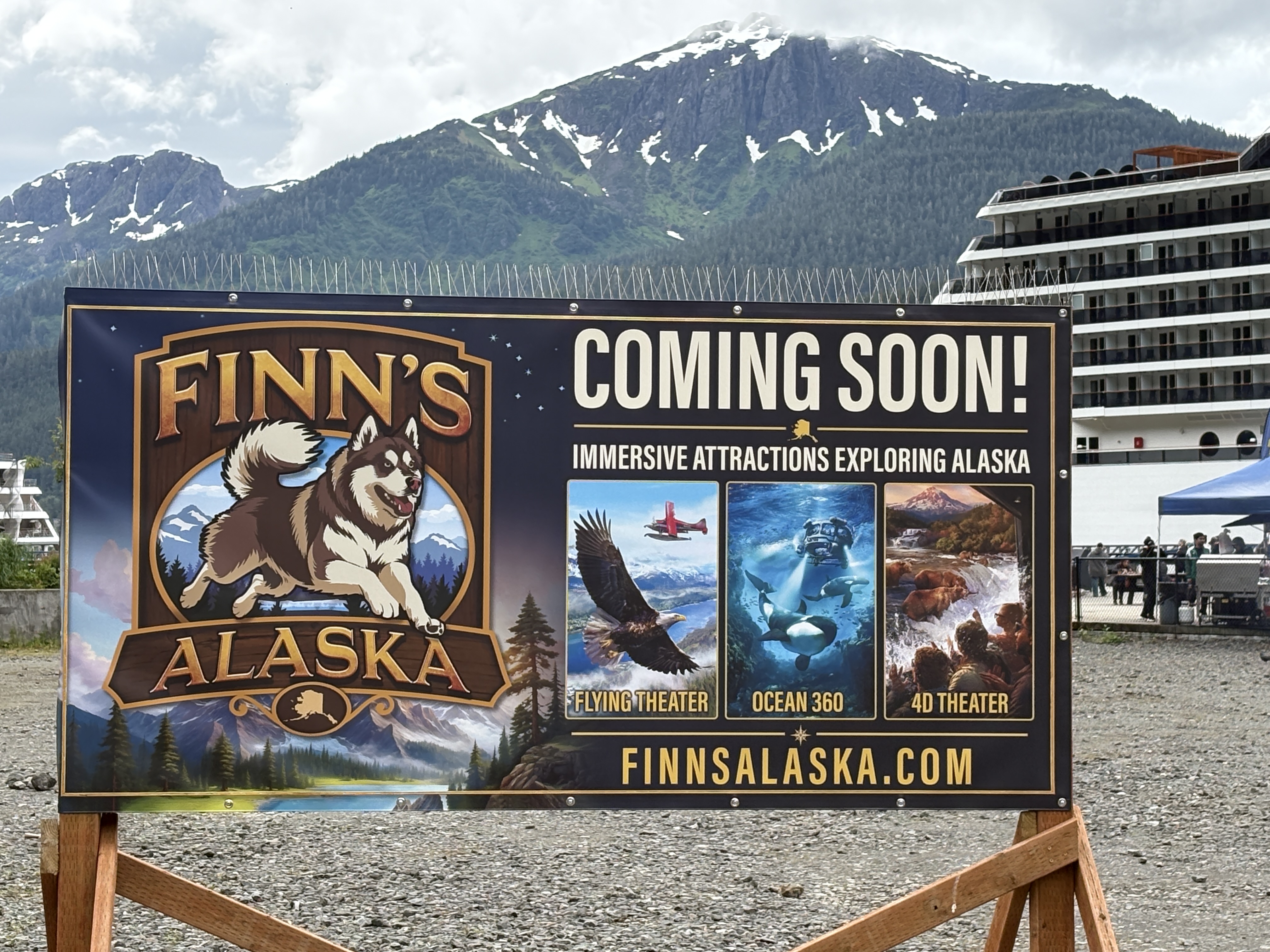 Finn's Alaska coming-soon sign on the South Franklin lot, cruise ship in port behind